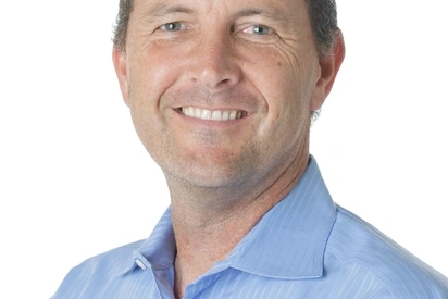 a white man in a light blue button down smiling at the camera