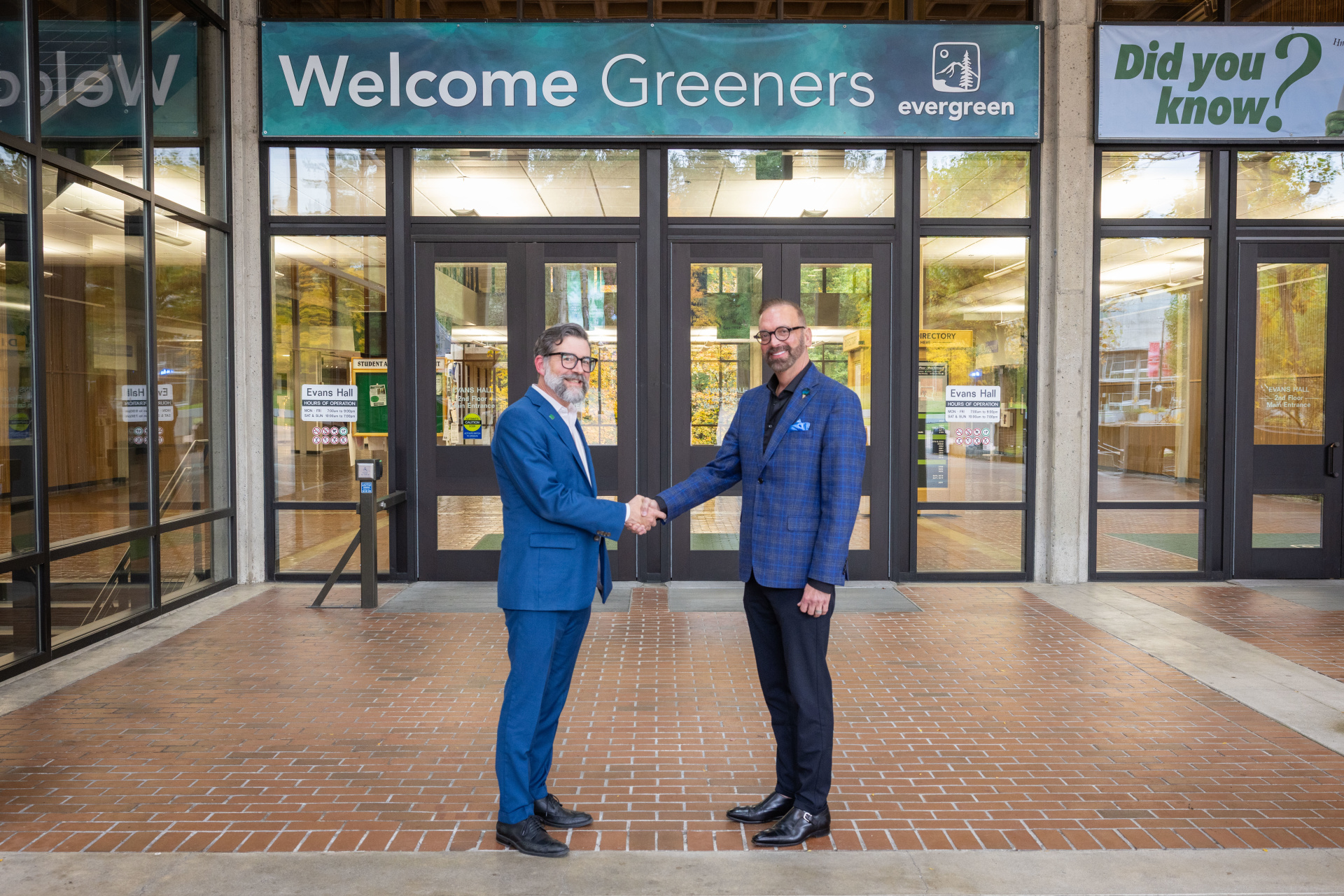 Dr. Timothy Stokes and Dr. John Carmichael shake hands in front of Evans Hall at Evergreen