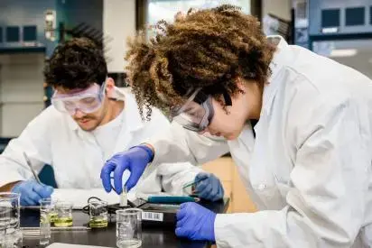 Two students working with lab equipment in a General Chemistry class