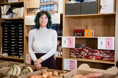 Woman standing behind boxes of food in the food bank