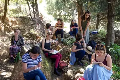 students sitting on a small hill covered in roots 