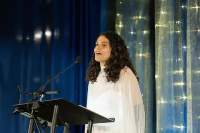 Woman with dark hair speaking at a podium