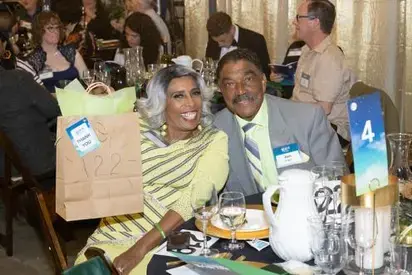 Two event attendees at event table holding up a gift bag