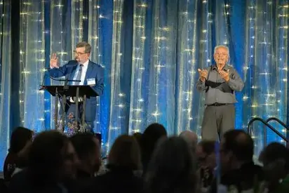 Person speaking on stage with sign-language interpreter next to them