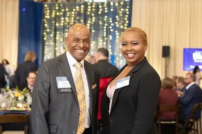 Two smiling people facing camera at an event