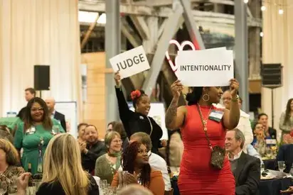 event attendees raise signs with the words judge and intentionality
