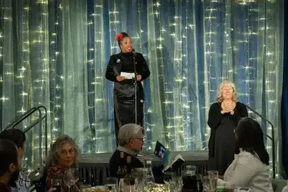 Person speaking on stage with sign-language interpreter next to them