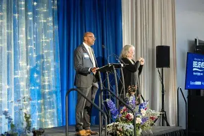 Person speaking on stage with sign-language interpreter next to them