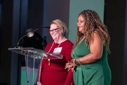 Two women standing at a podium addressing an off-camera audience