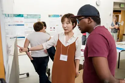 two people discussing a poster presentation at a conference 