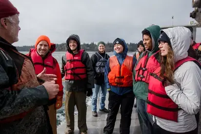 a group of students laughing and talking on the dock 
