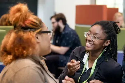 Image of two students in foreground and one in background at social event