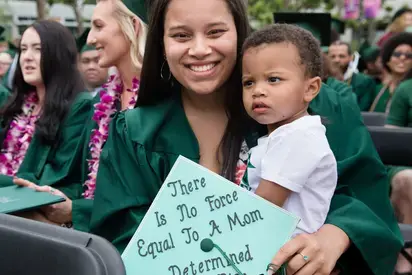 Mother holds their toddler at graduation