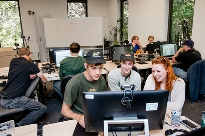 Three students work together while sitting around one computer