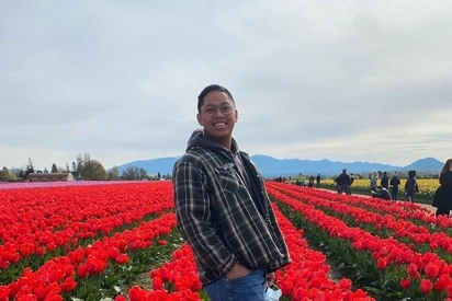 Nathan Deanon standing in a field of flowers