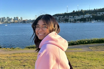 Enija looking at the camera over their shoulder with the puget sound behind them