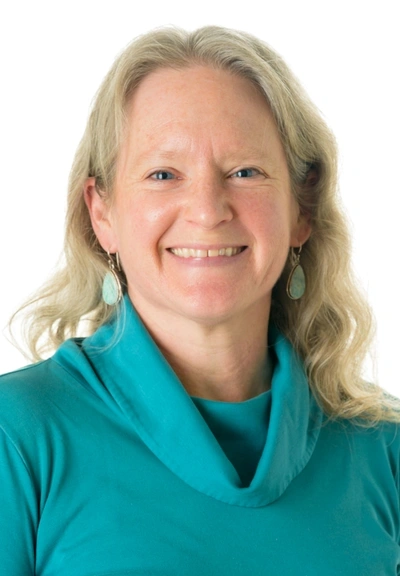 Photo of a person with long blond hair wearing a turquoise top and earrings