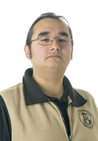 headshot of a person wearing rectagular glasses with whispy dark hair wearing a kayki fleece vest