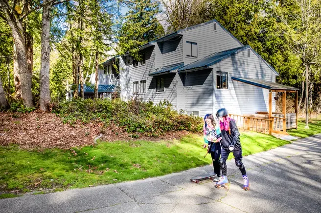 Two students rollerskate in from of the campus apartment buildings