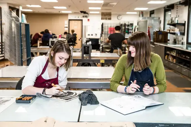 two students doing wood block carving at a shared table