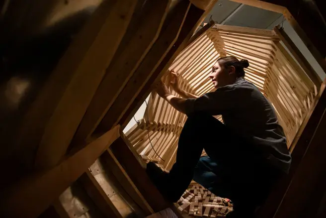 Student working inside wooden sculpture