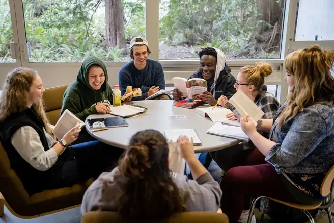 students around a circular table talking and reading