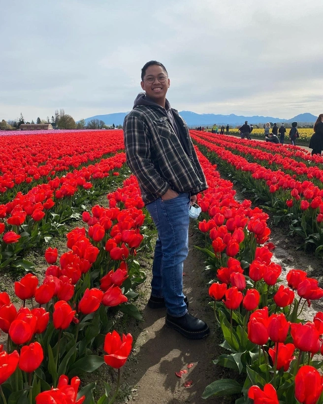 Nathan Deanon standing in a field of flowers