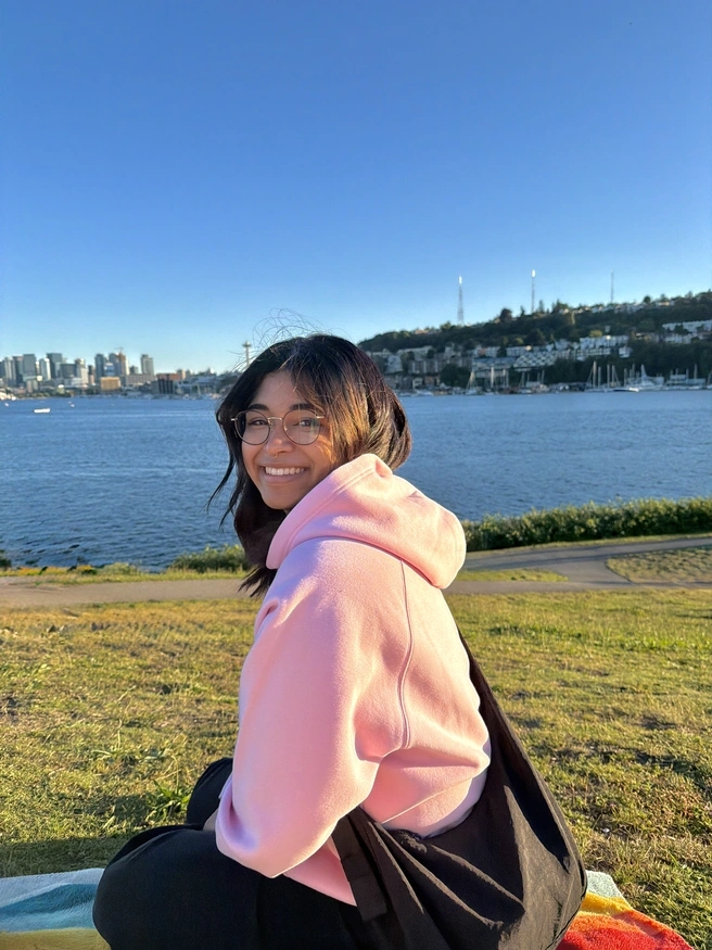 Enija looking at the camera over their shoulder with the puget sound behind them