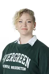 a photo of a white woman with short wavy blond hair wearing an evergreen crewneck sweater smiling at the camera