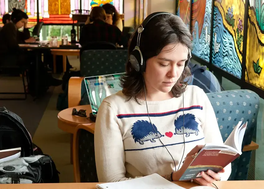 A student reads in the library while other students study in the background