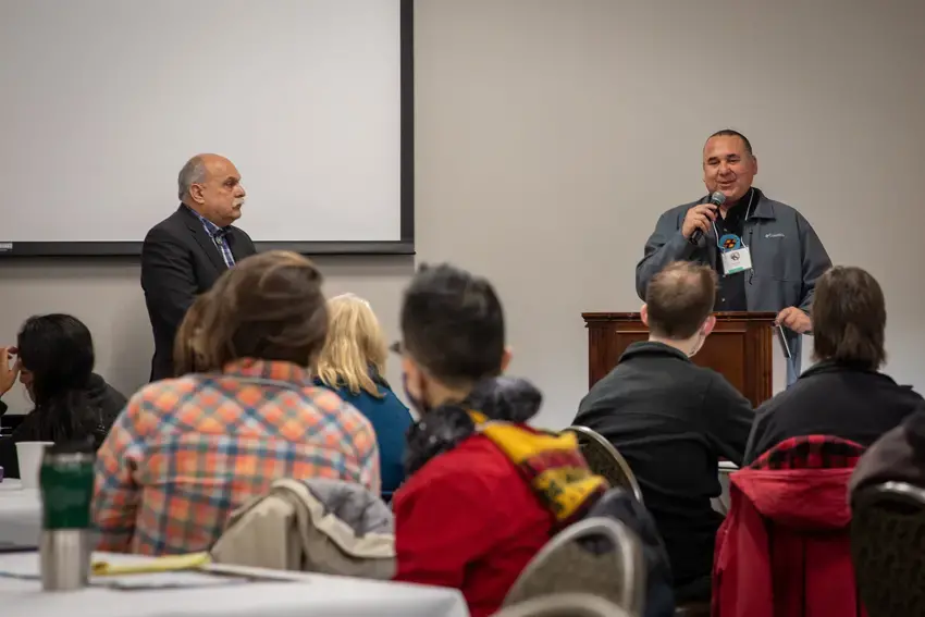 two men at the front of a room giving a keynote talk