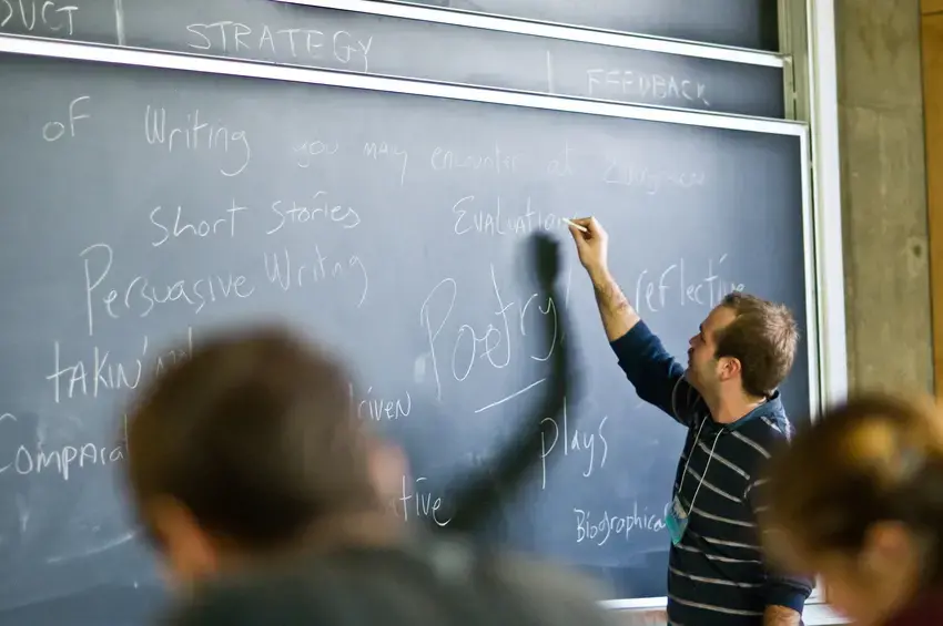 Person writing on a chalkboard during a writing workshop