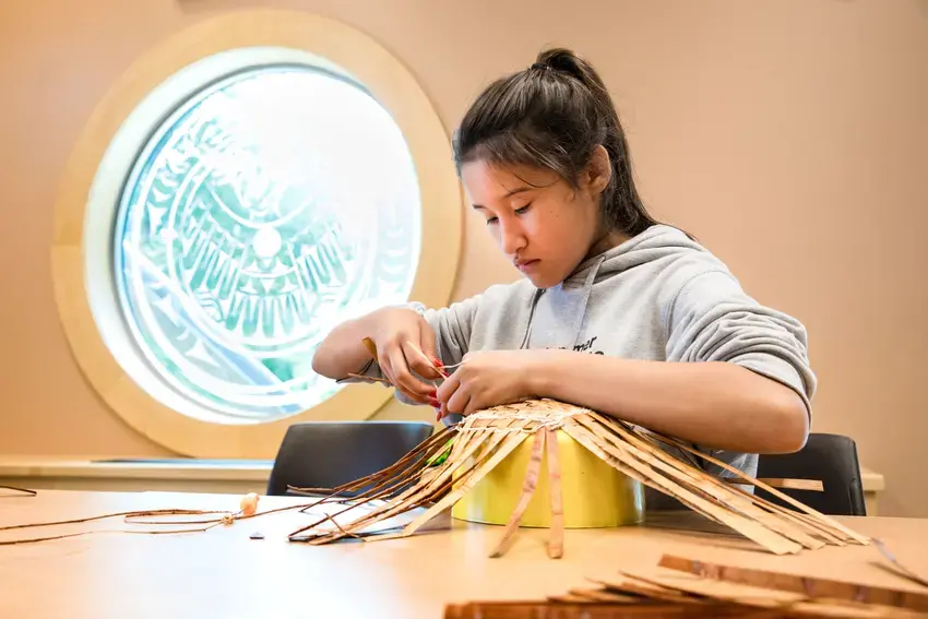 a person weaving a basket with their hands