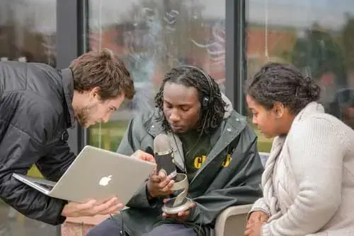 three students looking at a laptop