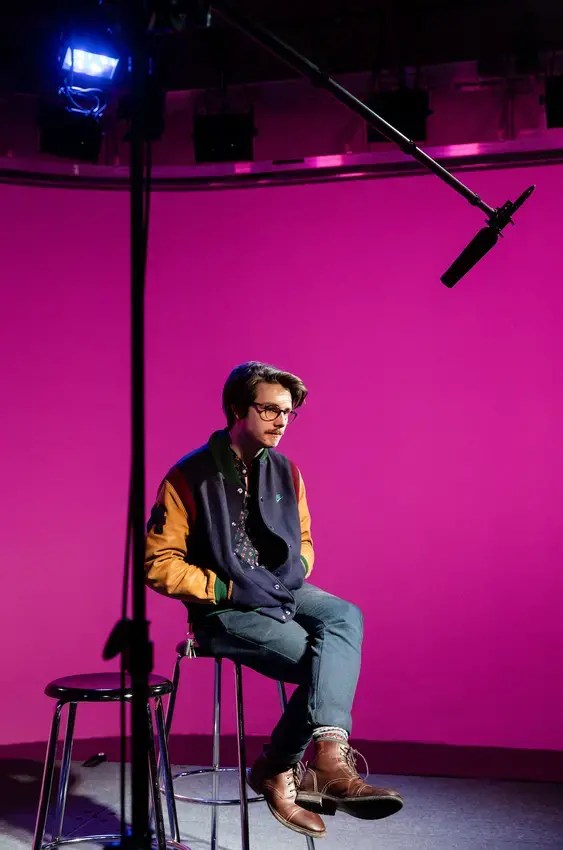student in television studio with magenta color background