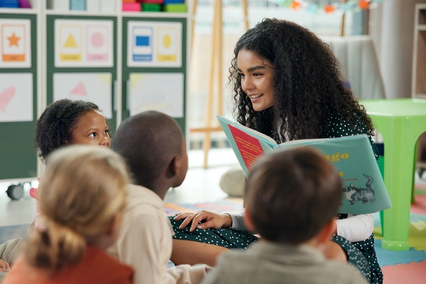 A teacher reading a book to young students