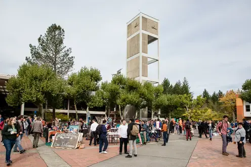 A large group of students gather outside in front of a clock tower