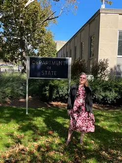 Christine Carlson standing in front of the Department of State sign in Washington, DC